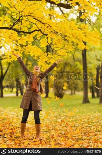 Happy woman throwing fallen leaves