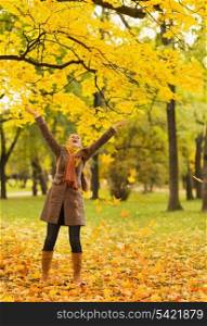 Happy woman throwing fallen leaves