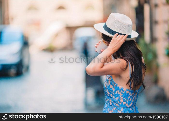 Happy woman tourist drinking hot drink coffee walking in street at Europe. Happy young urban woman drinking coffee in Europe. Caucasian tourist enjoy her european vacation in empty city