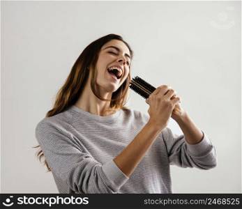 happy woman using hairbrush as microphone home