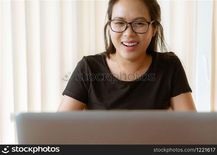 happy woman using laptop. Young Asian woman sitting at home and working on laptop