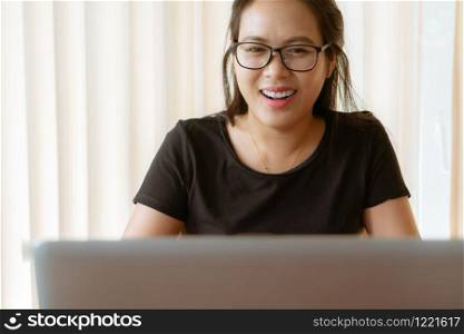 happy woman using laptop. Young Asian woman sitting at home and working on laptop