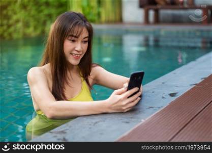 happy woman using smartphone in the swimming pool