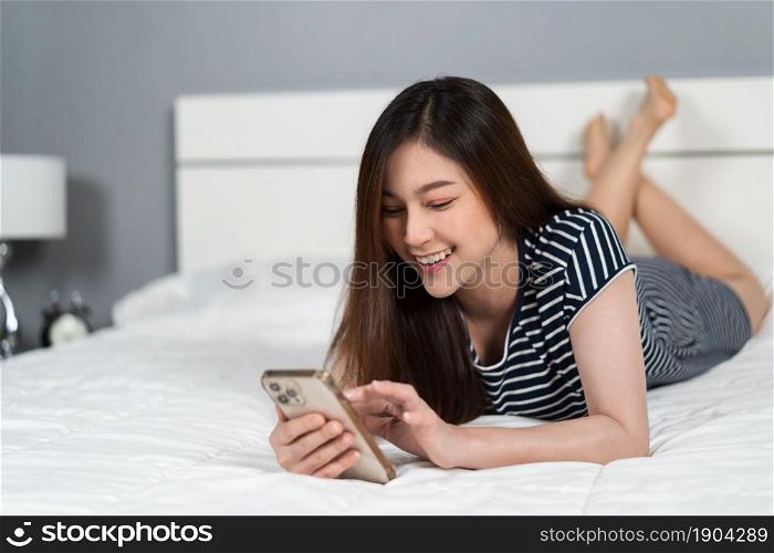 happy woman using smartphone on a bed