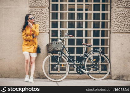 Happy woman walking in european street. Young attractive tourist outdoors in Vienna city on the piazza with the bike. Woman walking in city. Young attractive tourist outdoors in italian city