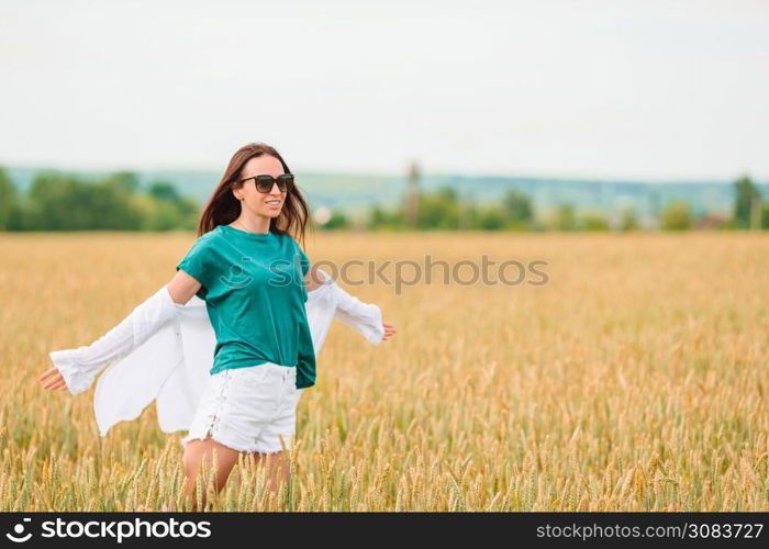 Happy woman walking in golden fields of wheat. Romantic woman walking in golden fields of wheat