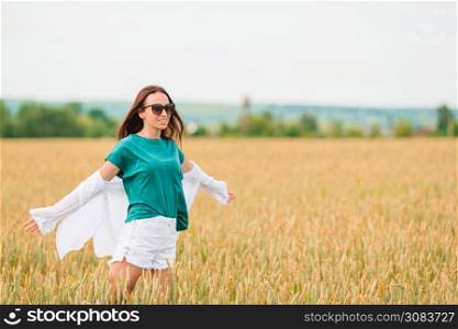 Happy woman walking in golden fields of wheat. Romantic woman walking in golden fields of wheat