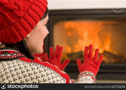 Happy woman warming up by home fireplace wear Christmas sweater