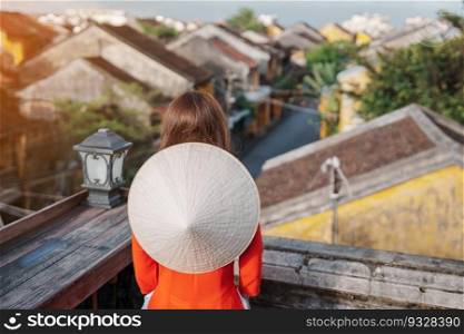 happy woman wearing Ao Dai Vietnamese dress, traveler sightseeing view at rooftop in Hoi An ancient town. landmark and popular for tourist attractions. Vietnam and Southeast travel concept