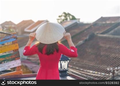 happy woman wearing Ao Dai Vietnamese dress, traveler sightseeing view at rooftop in Hoi An ancient town. landmark and popular for tourist attractions. Vietnam and Southeast travel concept