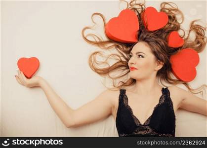 Happy woman wearing lingerie in bed at home. Attractive seductive young girl with heart shape boxes around head. Female underwear fashion. Valentines day love.. Woman in lingerie in bed. Valentines day love.