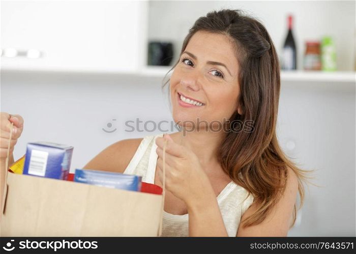 happy woman with a bag of groceries shopping at home