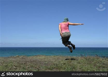 happy woman with a big jump at the coast