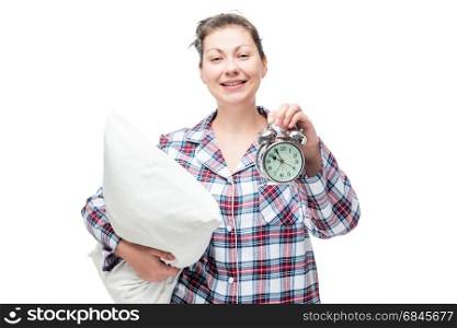 Happy woman with a pillow in her hand shows later time on the al. Happy woman with a pillow in her hand shows later time on the alarm clock