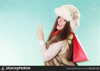Happy woman with bag shopping. Winter fashion.. Happy charming gorgeous woman with bag shopping. Young girl in fur hat in studio blue. Winter fashion clothes sale.