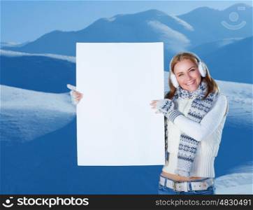 Happy woman with big blank postcard in hands standing in the snowy mountains, copy space for advertisement, happy winter holidays&#xA;