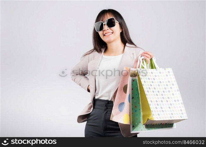Happy woman with glasses confident shopper smiling holding online shopping bags colorful multicolor, Portrait excited Asian young female purchase studio shot isolated on white background, fashion sale