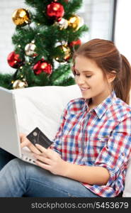 happy woman with laptop computer and credit card over christmas tree....