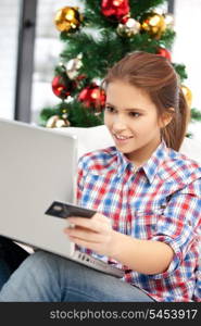 happy woman with laptop computer and credit card over christmas tree....