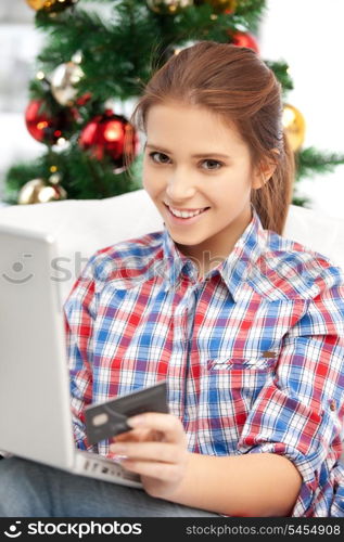 happy woman with laptop computer and credit card over christmas tree....