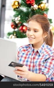 happy woman with laptop computer and credit card over christmas tree