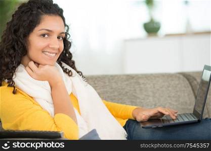 happy woman with laptop on sofa at home