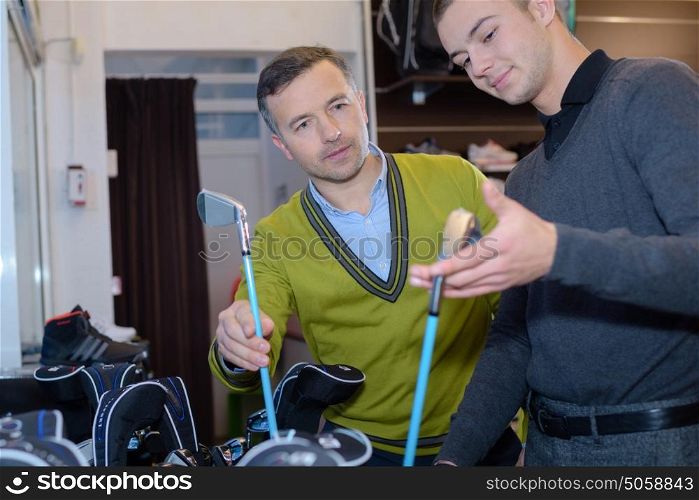 happy woman with man selecting golf club in store