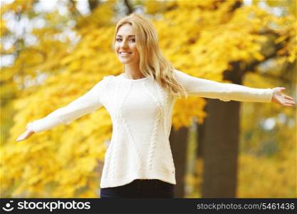 Happy woman with raised hands in autumn park