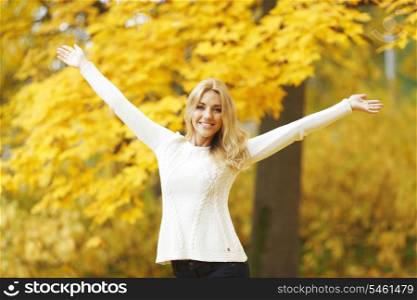 Happy woman with raised hands in autumn park