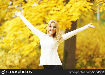 Happy woman with raised hands in autumn park