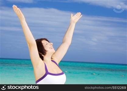 happy woman with raised hands on the beach