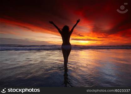 Happy woman with raised hands on the beach at sunset, Bali, Seminyak, Double six beach