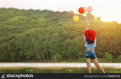 Happy woman with red hat playing balloons at outdoor with copy space . Relax and happy concept. woman with red hat playing balloons