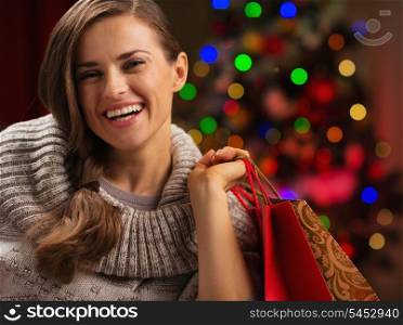 Happy woman with shopping bag in front of Christmas lights