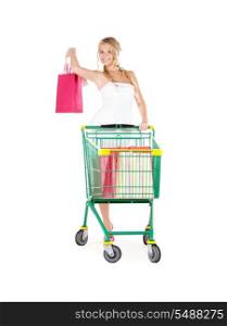 happy woman with shopping bags and cart over white