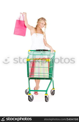 happy woman with shopping bags and cart over white