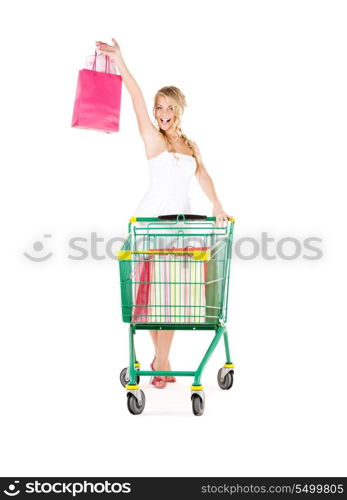 happy woman with shopping bags and cart over white