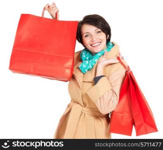 Happy woman with shopping bags in beige autumn coat with green scarf - isolated on white background