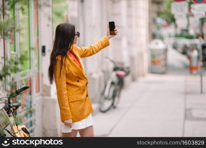 Happy woman with smartphone in european street. Young attractive tourist outdoors in Vienna city. Woman talk by her smartphone in city. Young attractive tourist outdoors in italian city