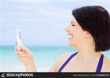 happy woman with white phone on the beach