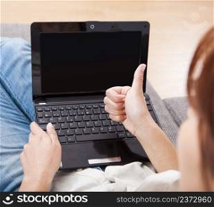 Happy woman working on a laptop with thumbs up signal