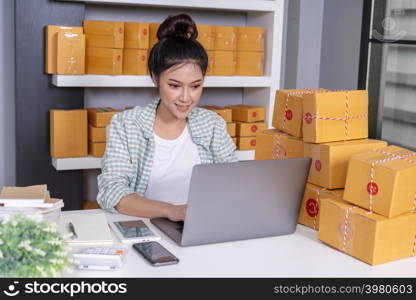 happy woman working with her laptop computer and courier parcel box at home office