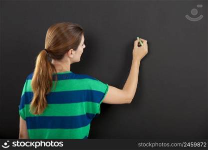 Happy woman writing on  chalkboard, with copy space for designer