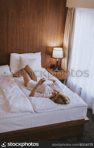 Happy womanl using a mobile phone while lying on the bed at home