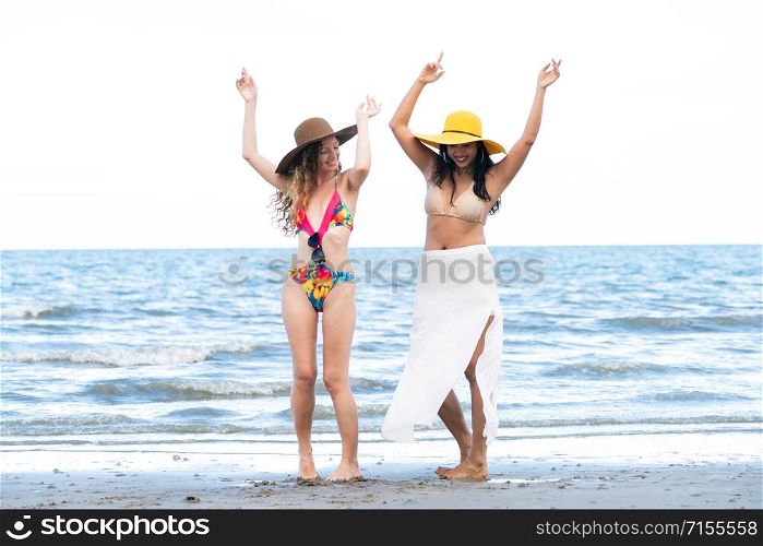Happy women friends are on vacation at tropical sand beach in summer.. Happy women dance on sand beach in summer.