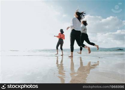 Happy women friends runs at sea beach during a bright day, friends happy relax having fun playing on beach near sea when sunset in evening.