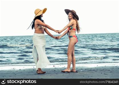 Happy women in bikinis dance together on tropical sand beach in summer vacation. Travel lifestyle.. Happy women dance on sand beach in summer.