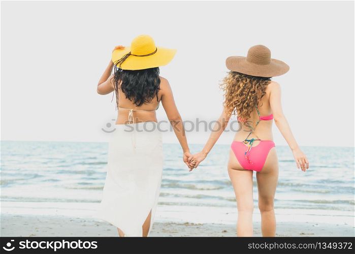 Happy women in bikinis go sunbathing together on tropical sand beach in summer vacation. Travel lifestyle.. Happy women go sunbathing at sand beach in summer.