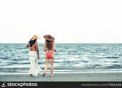 Happy women in bikinis go sunbathing together on tropical sand beach in summer vacation. Travel lifestyle.. Happy women go sunbathing at sand beach in summer.