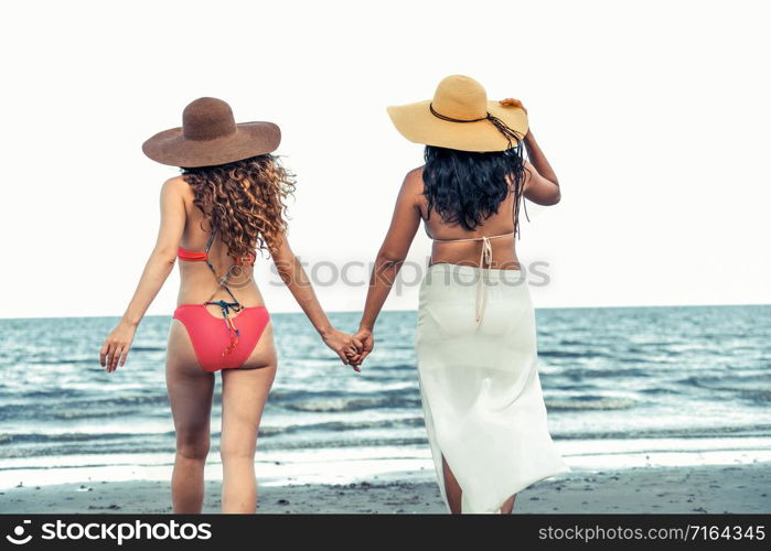 Happy women in bikinis go sunbathing together on tropical sand beach in summer vacation. Travel lifestyle.. Happy women go sunbathing at sand beach in summer.